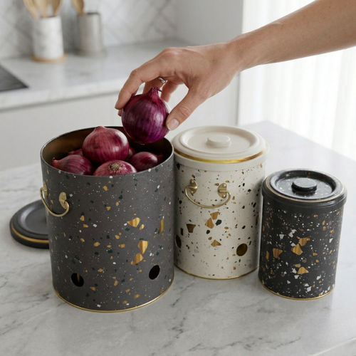 Person placing an onion into a terrazzo-patterned kitchen storage container on a marble countertop.


